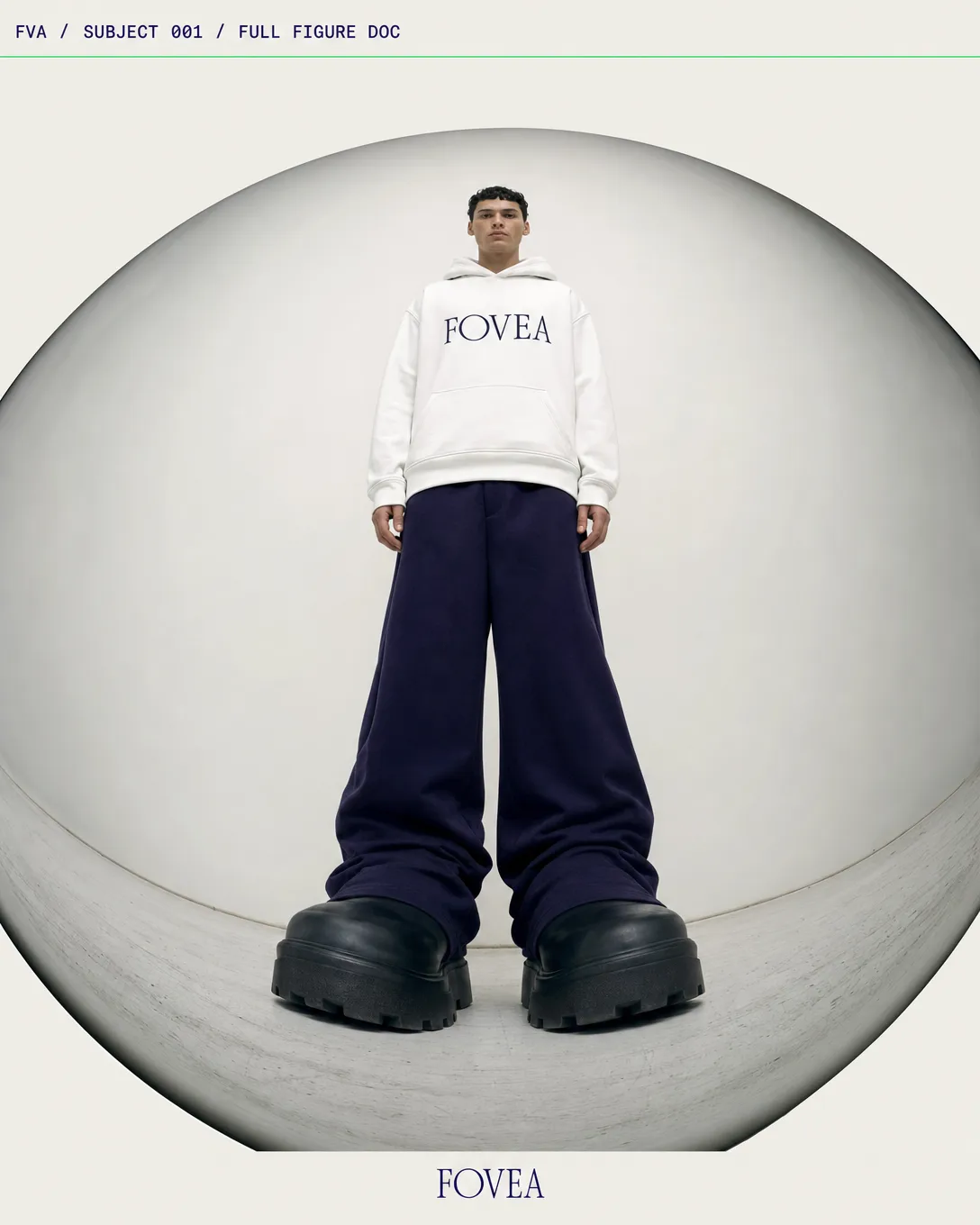 A full-figure fisheye document of a FOVEA hoodie with exaggerated footwear and contained white backdrop.